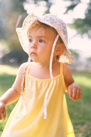 Little girl in a panama hat and a dress looks thoughtfully into the distance. Portraitの写真素材