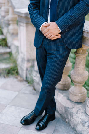 Man in a suit stands near the steps, leaning on a handrailの写真素材