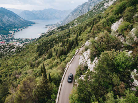 A man and a woman are driving in an open car along a scenic trail in the mountains in Montenegroの写真素材