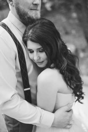 The groom gently hugs the bride, who leaned against his chest and closed her eyes, black and whiteの写真素材