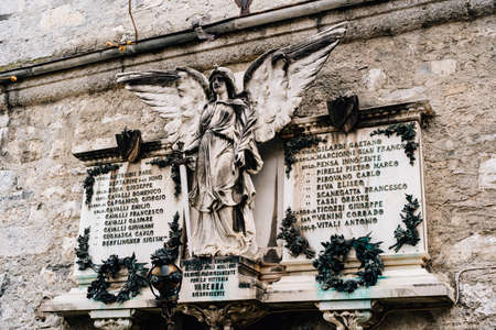 Memorial panel with a sculpture of an angel in the Varenna cemetery, Italyの写真素材