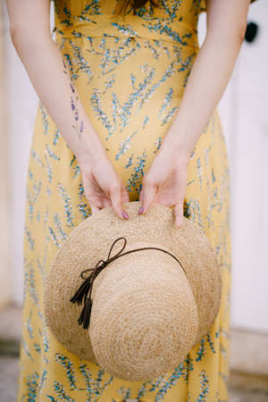 Girl holding a straw hat behind her backの写真素材