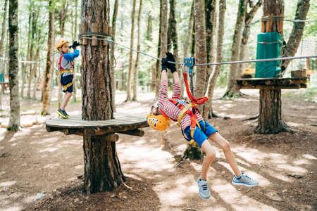Boy climbs the zip line holding on to the safety ropesの写真素材