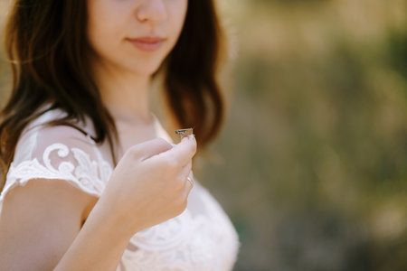 Bride in a white dress holds a grasshopper on her hand. Portraitの写真素材