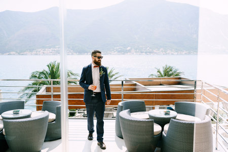 Groom walks along the hotel terrace against the backdrop of the sea and mountainsの写真素材