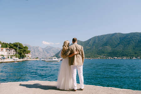 Newlyweds stand hugging each other on the pier and look at the seaの写真素材