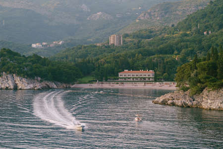 Motor boat sails along the bay from the beach of Villa Milocer. Montenegro