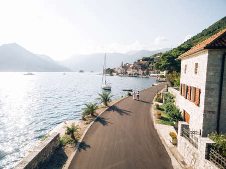 Bride and groom walk along the asphalt road along the coast of Perast. Montenegroの写真素材