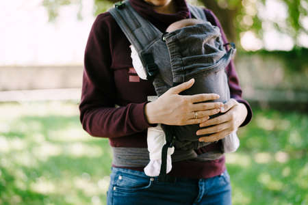 Mom hands hug the baby in a sling. Close-upの写真素材