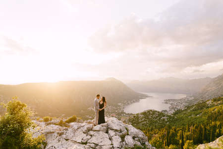Man hugs woman on the top of a rocky mountain in the background of the bayの写真素材