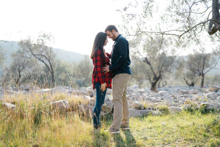 Man holding hands on belly of pregnant woman while standing in parkの写真素材