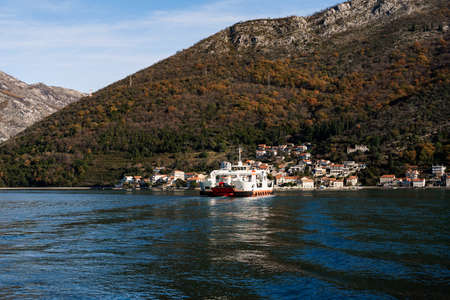 Large ship sails to a town on the coast of the sea at the foot of the mountains