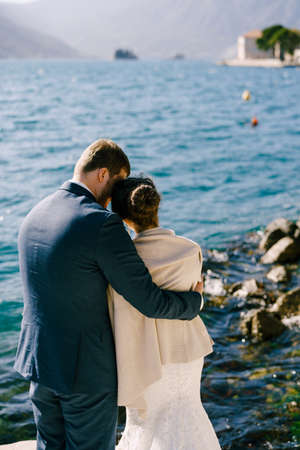 Bride and groom hug on the shore of the bay. Back viewの写真素材