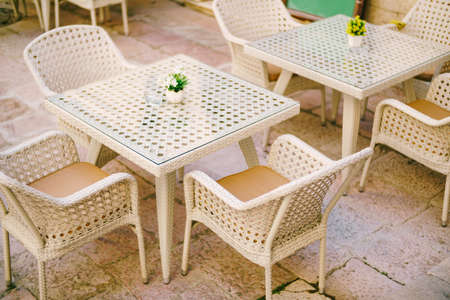 Openwork chairs around the tables stand on the tiles in the streetの写真素材