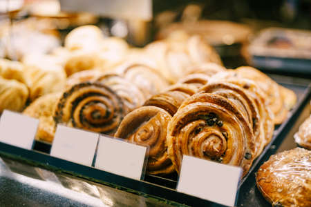 Round buns with icing and raisins lie on a shop window