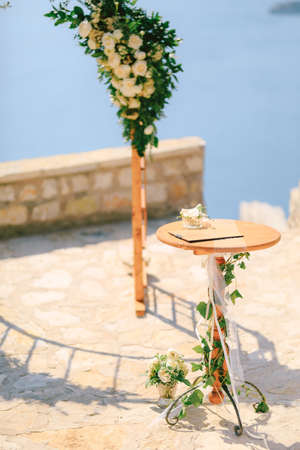Small table stands in front of the wedding arch on an observation deck overlooking the seaの写真素材