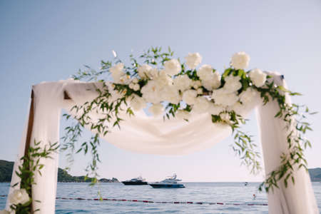 Fragment of a wedding arch decorated with white tulle and flowersの写真素材