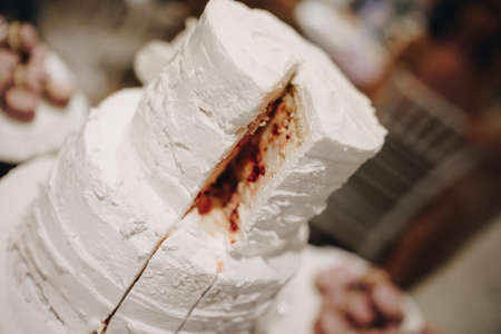 White three-tiered wedding cake with cut-out piece
