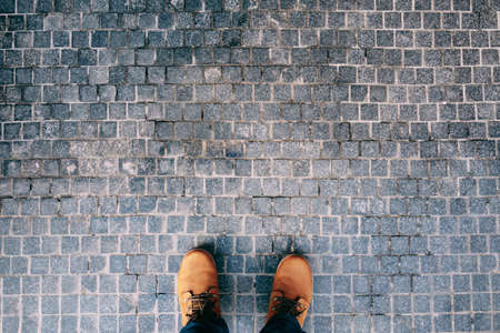 Male feet in brown boots stand on the cobblestones. Close-upの写真素材