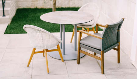 Armchairs and chairs near a round table on a tile in the street