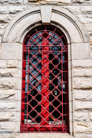 Red forged lattice on the arched window of an ancient building