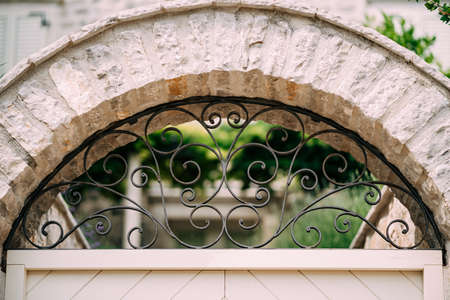 Arched metal forged lattice in a stone fence. Close-up