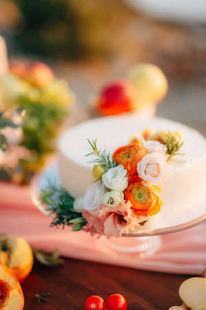 White wedding cake decorated with roses stands on a tableの写真素材