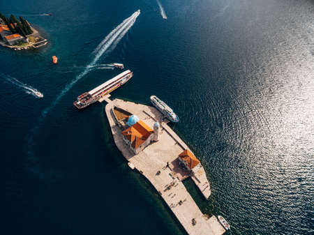Boats moored near the island of Gospa od Skrpjela on the background of St. George island. Top view