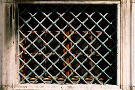 Rectangular metal lattice in front of a window on the facade of the building. Close-upの写真素材