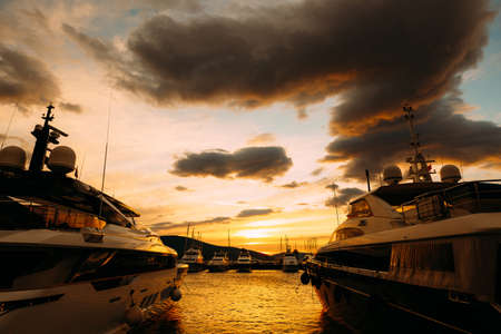 Yachts moored in Porto Montenegro against the backdrop of an orange sunsetの写真素材