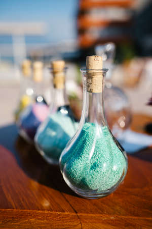 Glass bottles with colored sand are on the tableの写真素材
