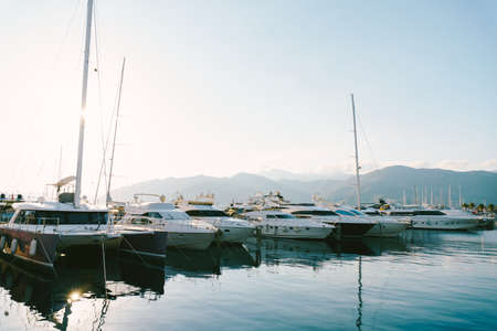 Yachts are moored to the pier against the backdrop of mountains in Porto Montenegroの写真素材