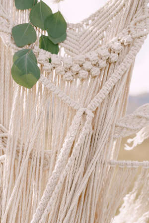Knitted lace white macrame decorated with green leavesの写真素材