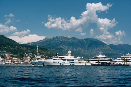 Luxurious white superyachts stand at Porto marina with mountains in the background
