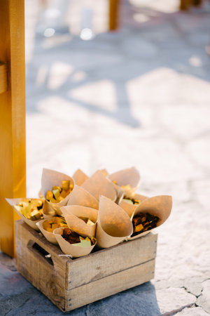 Box with flower petals in rolled sheets of paper stands on a stone floorの写真素材