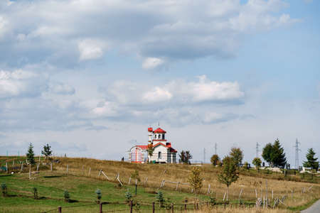 White brick church with red roof in the fieldの写真素材
