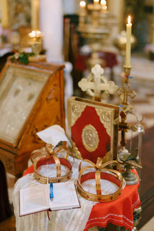 Cross, golden crowns, a bible and candlesticks are on the table in the churchの写真素材