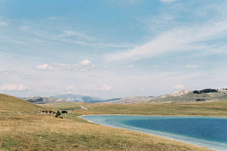 Clear blue lake in the valley against the backdrop of the mountainsの写真素材