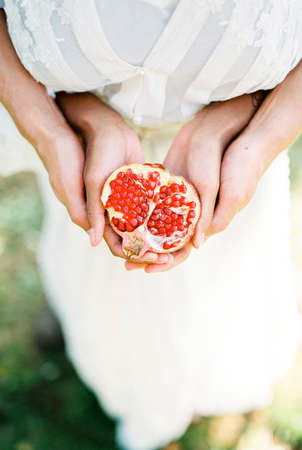 Man hugging a woman holding half a pomegranate in her handsの写真素材