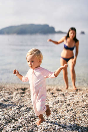 Little girl walks barefoot on a pebble beachの写真素材