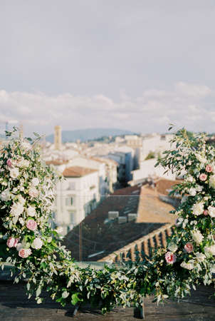 Wedding semi-arch of flowers on the terrace of the building overlooking the roofs of the housesの写真素材