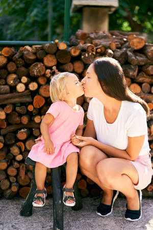 Mom kisses a little girl squatting next to her