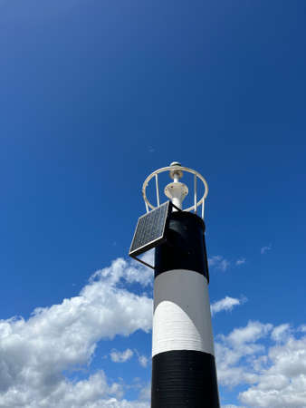 Black and white lighthouse tower against a cloudy skyの写真素材