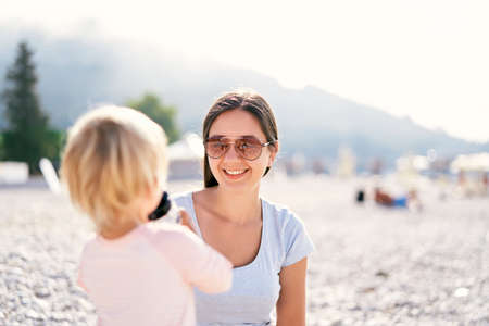 Smiling mother looking at little girl drinking from a bottleの写真素材