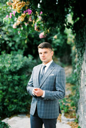 Man in a gray checkered suit stands under a flowering treeの写真素材