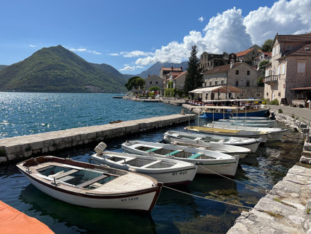 Budva, Montenegro - 01.08.22: Row of boats on the pier off the coast of Perast against the backdrop...