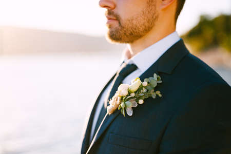 Young groom in a stylish suit with a boutonniere under the sunlightの写真素材