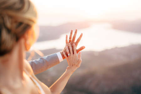The bride and groom stand on Mount Lovcen overlooking the Bay of Kotor, the bride put her hand on the grooms handの写真素材