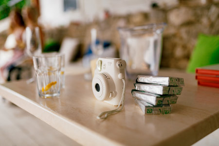 Tivat, Montenegro - 15 april 2021: Fujifilm Instax Square SQ1 white camera with spare film cartridges stands on a wooden tableのeditorial素材