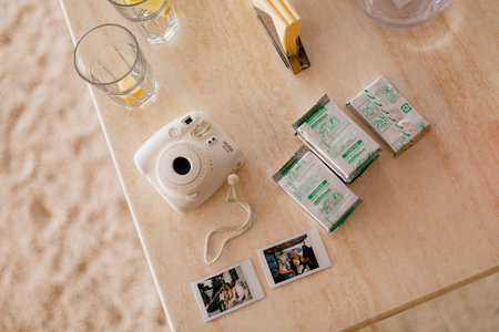 Tivat, Montenegro - 15 april 2021: Fujifilm Instax Mini 8 white camera with spare film cartridges and instant photos lies on a wooden tableのeditorial素材